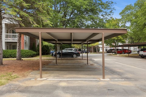 A carport with a metal roof is situated in a parking lot.