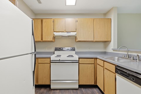 A kitchen with a white refrigerator, white stove, and wooden cabinets.