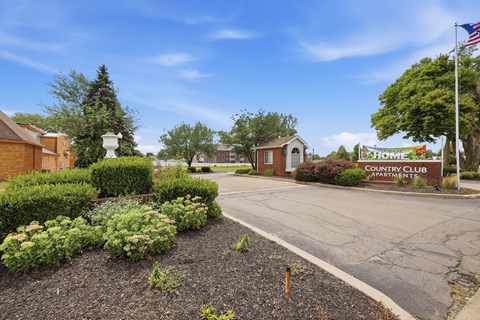 The entrance to the Country Club Apartments is surrounded by a well-maintained garden.