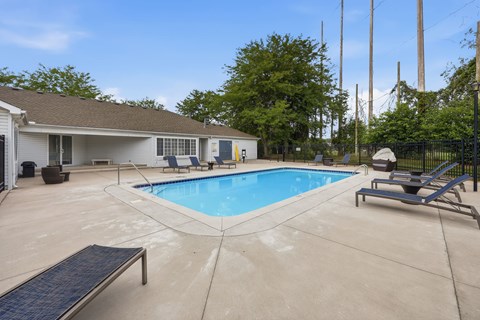 A pool with a bench and a house in the background.