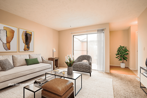 A living room with a couch, chair, and two paintings on the wall.