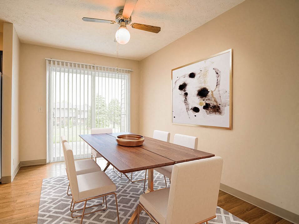 a dining room with a ceiling fan and a large painting on the wall