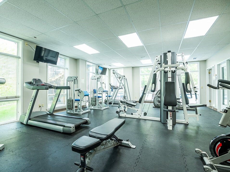 a gym with cardio equipment and TV