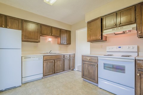 A kitchen with white appliances and wooden cabinets.