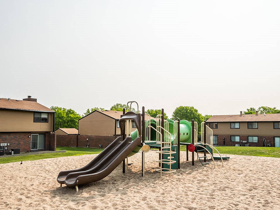 a playground with a slide in the middle of sand