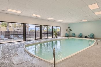 a large indoor swimming pool with patio furniture