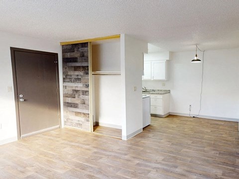 an empty living room and kitchen with a wood floor