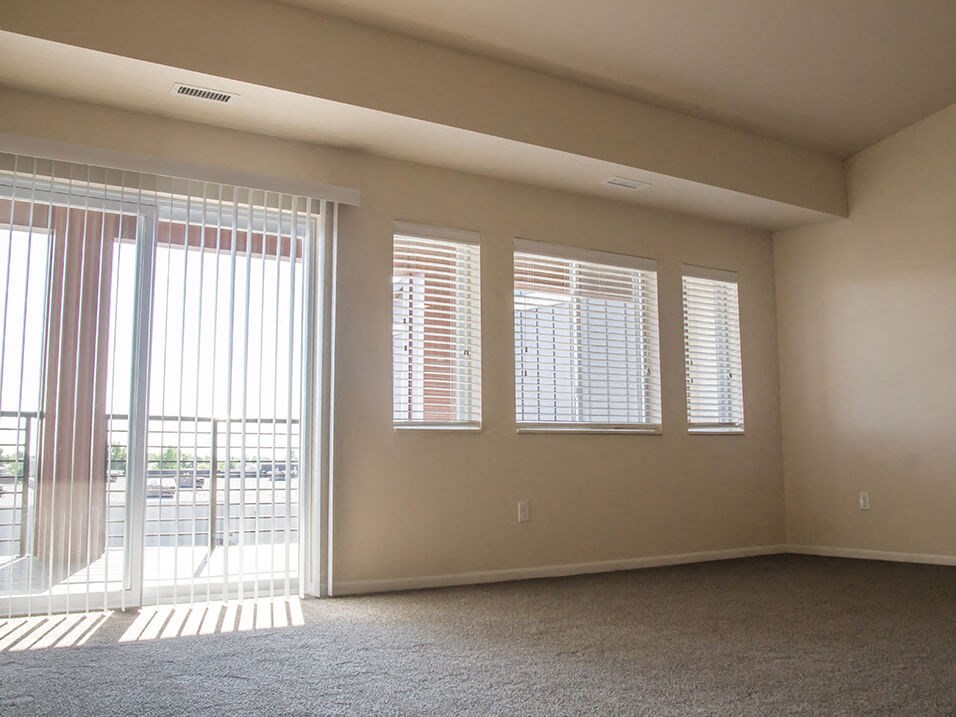 an empty room with a sliding glass door and four windows