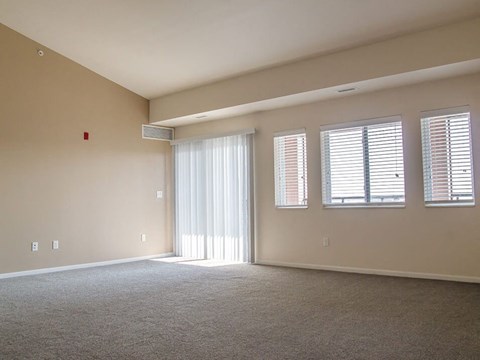 an empty room with a sliding glass door and three windows