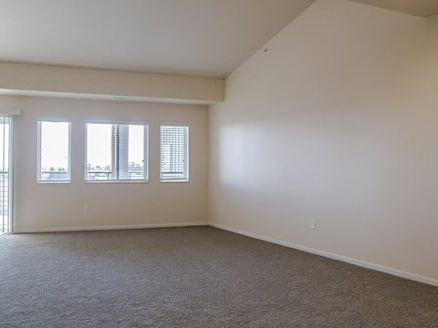 a bedroom with three windows and a carpeted floor