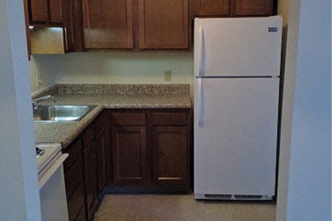 A white refrigerator in a kitchen with brown cabinets.