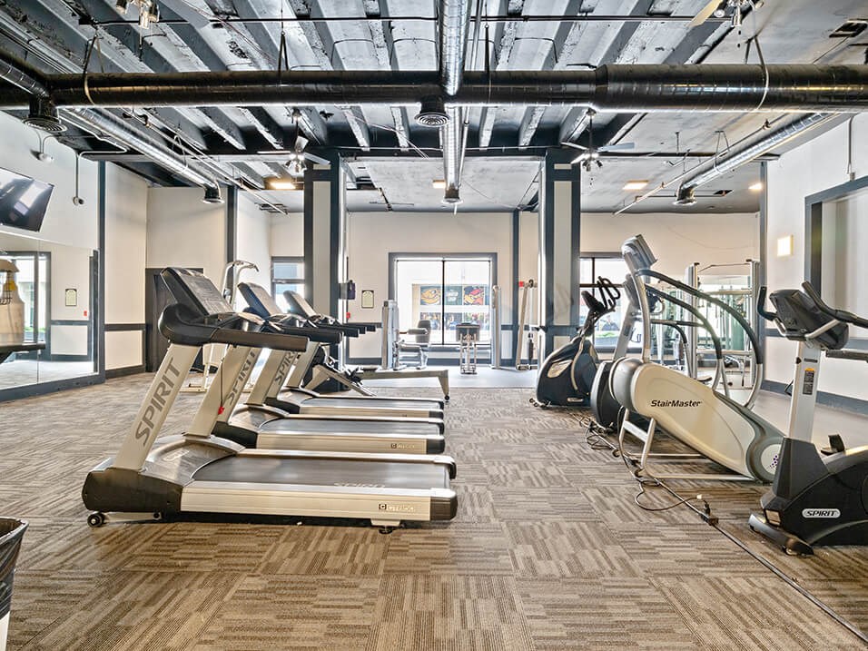 a gym with cardio equipment and weights on the floor