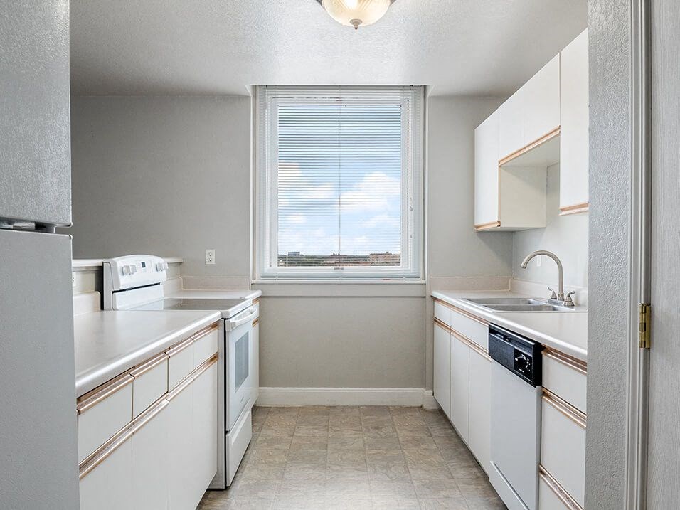 apartment kitchen with white appliances and a window