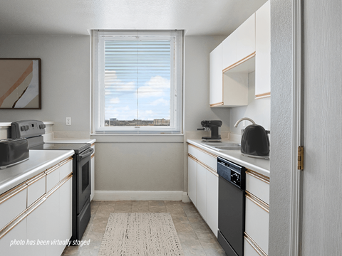 A kitchen with white cabinets and a black dishwasher.