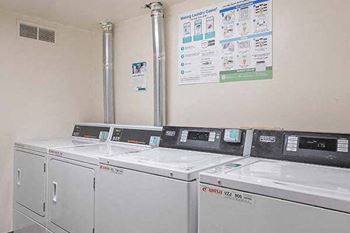 a row of white washing machines in the on-site laundry room