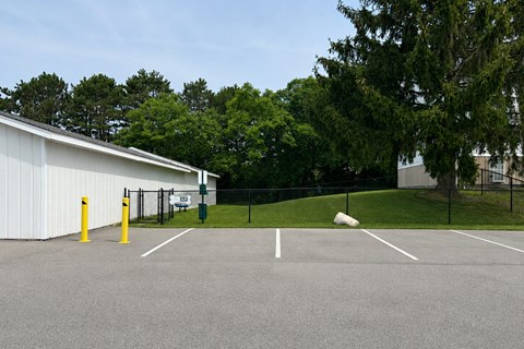 A parking lot with a white building and yellow bollards.