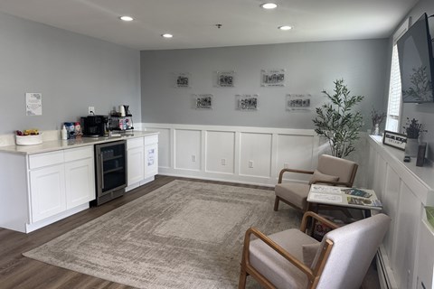 A white kitchen with a rug on the floor and two chairs.