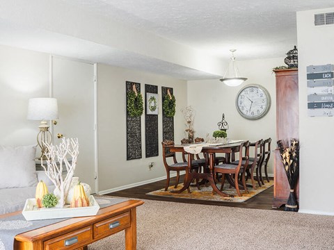 a living room with a dining room table and a clock on the wall