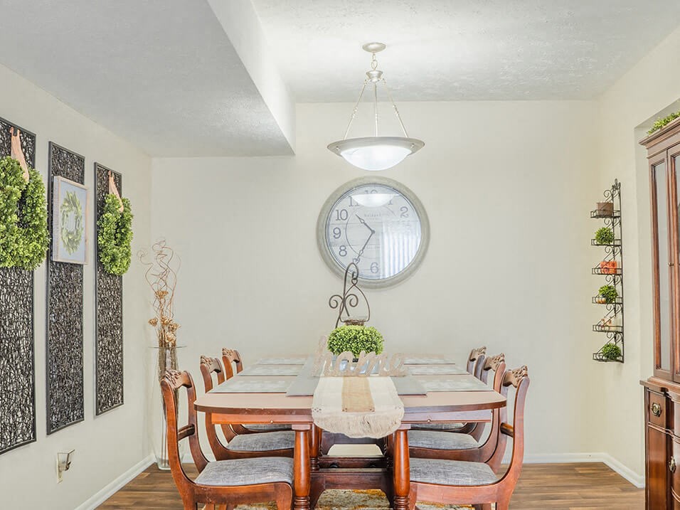 a dining room with a table and chairs and a large clock on the wall