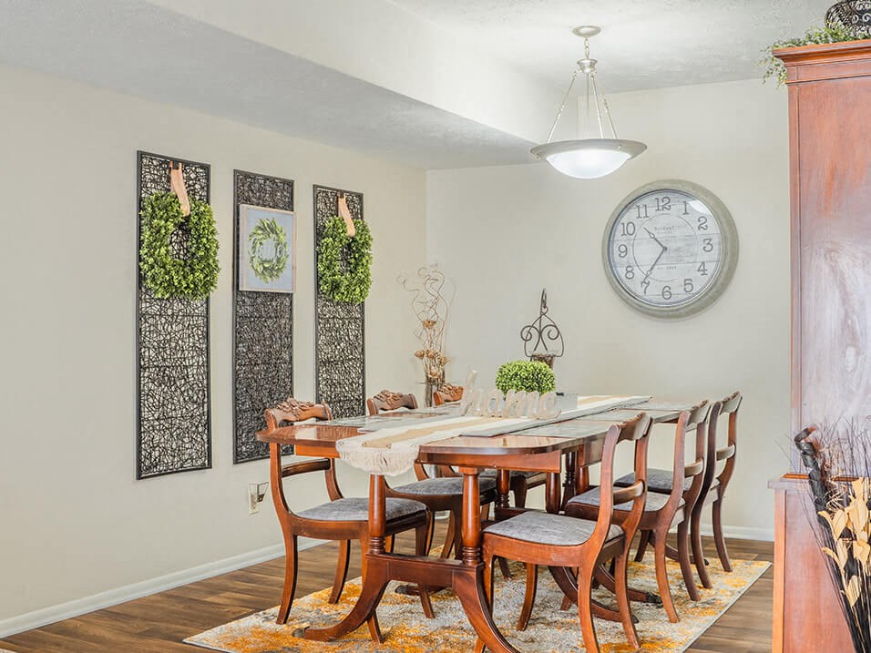 a dining room with a table and chairs and a clock on the wall