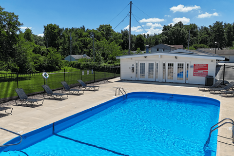 A pool with a blue tiled edge and a white building in the background.