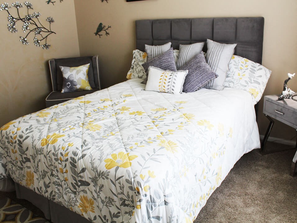 a bedroom with a large bed with a white and yellow comforter and pillows