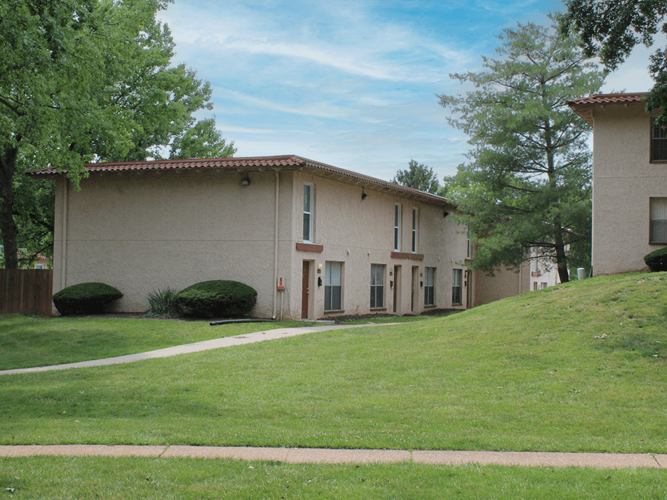 the front of a tan building with a green lawn