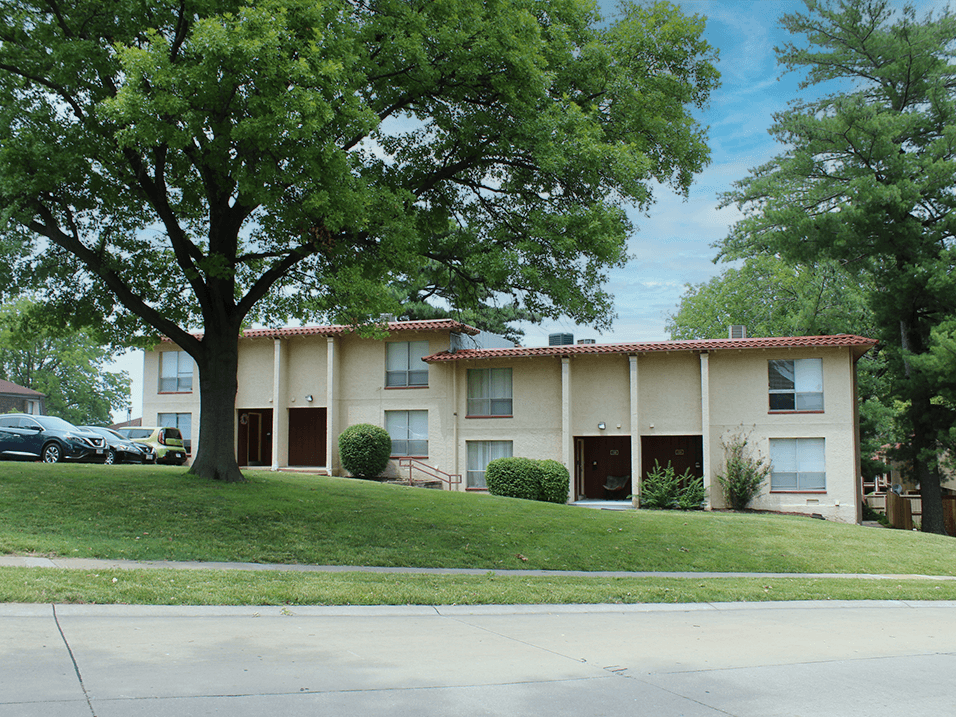 a large apartment complex with trees in front of it