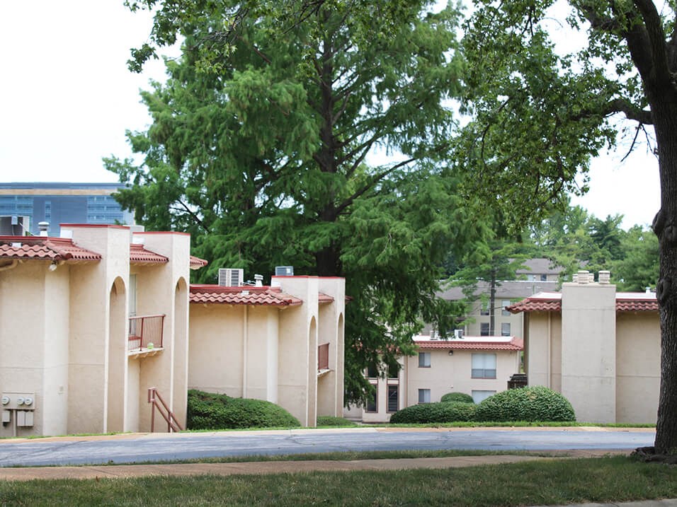 an apartment complex with trees in the foreground and a building in the background
