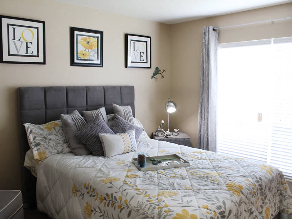 a bedroom with a large bed with a white and yellow comforter