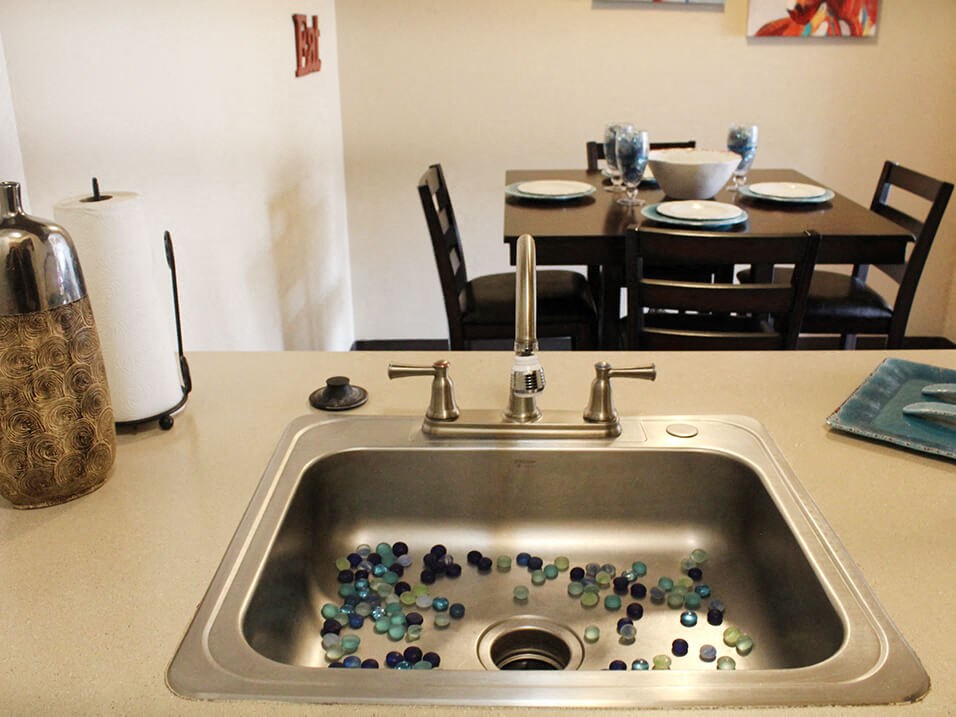a sink with marbles in it and a dining room table and chairs in the background