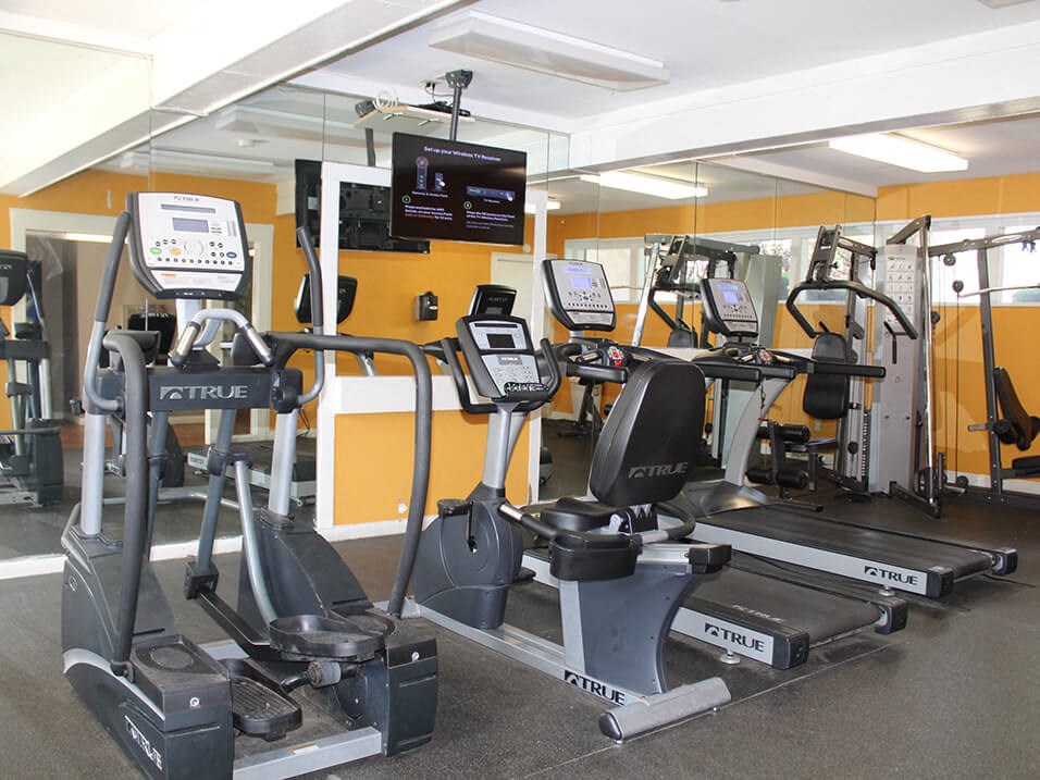 fitness room filled with lots of exercise equipment