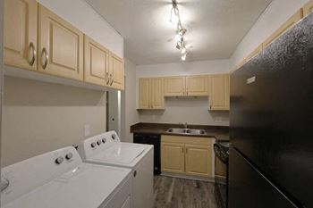 A kitchen with a white washing machine and a black fridge.