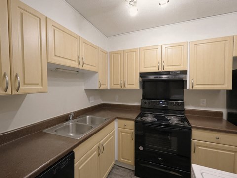 A kitchen with a black oven and brown countertops.