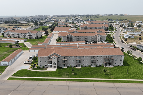 A large apartment complex with a parking lot in front.
