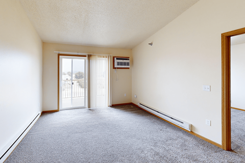A sparsely furnished room with a sliding glass door.