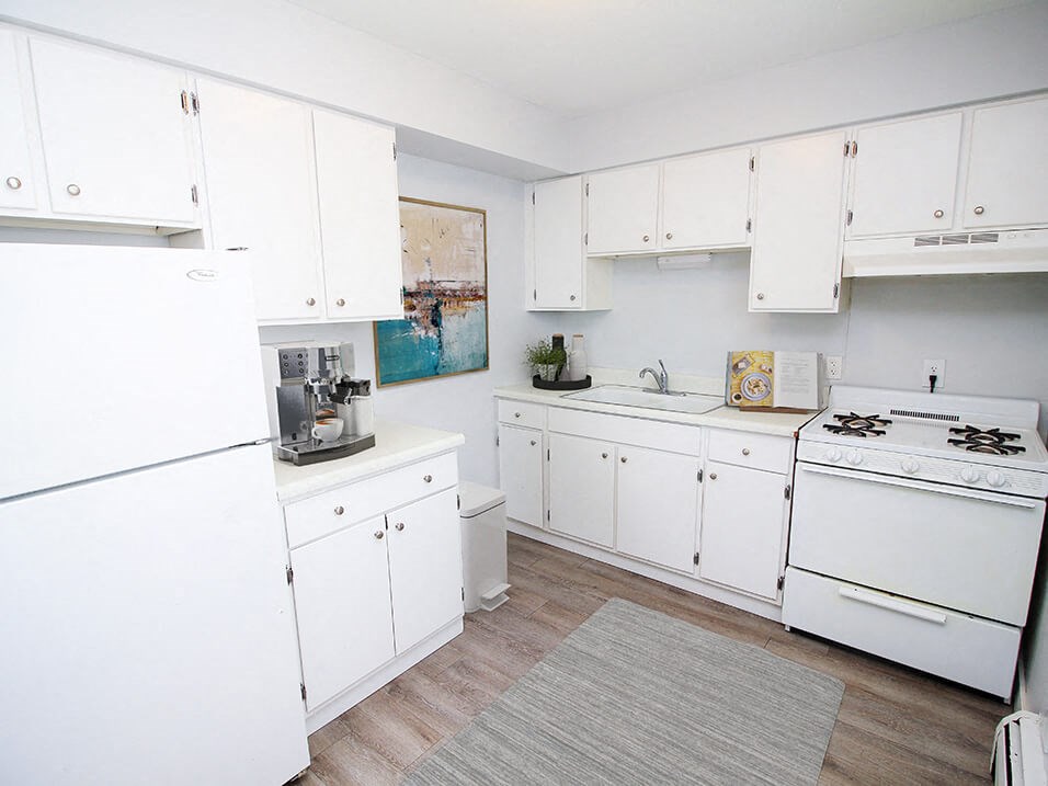 apartment kitchen with white cabinets and white appliances