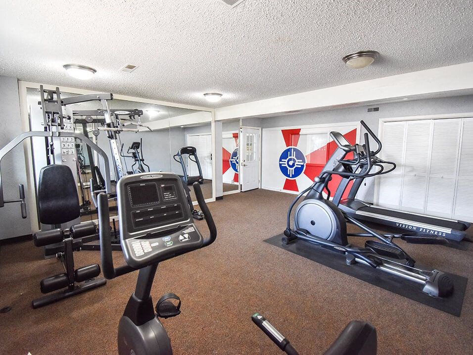 a gym with exercise machines and other equipment in a room with flags