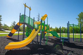 a playground with a slide and other playground equipment at an apartment community