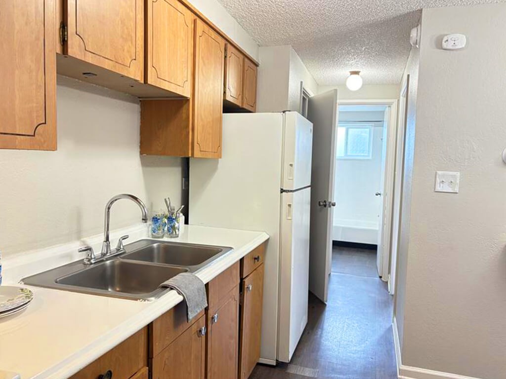 A kitchen with wooden cabinets and a white fridge.