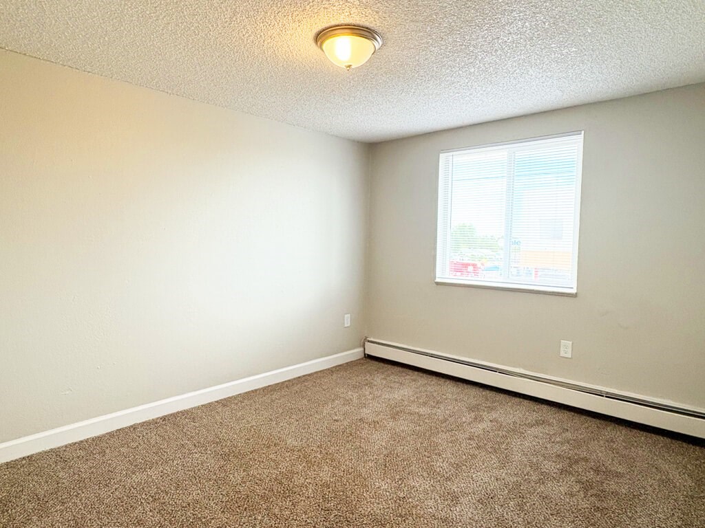 A room with a carpeted floor and a window.