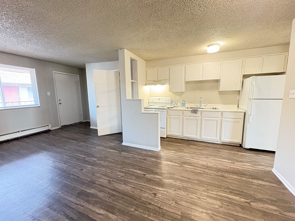 A kitchen with white appliances and wooden floors.