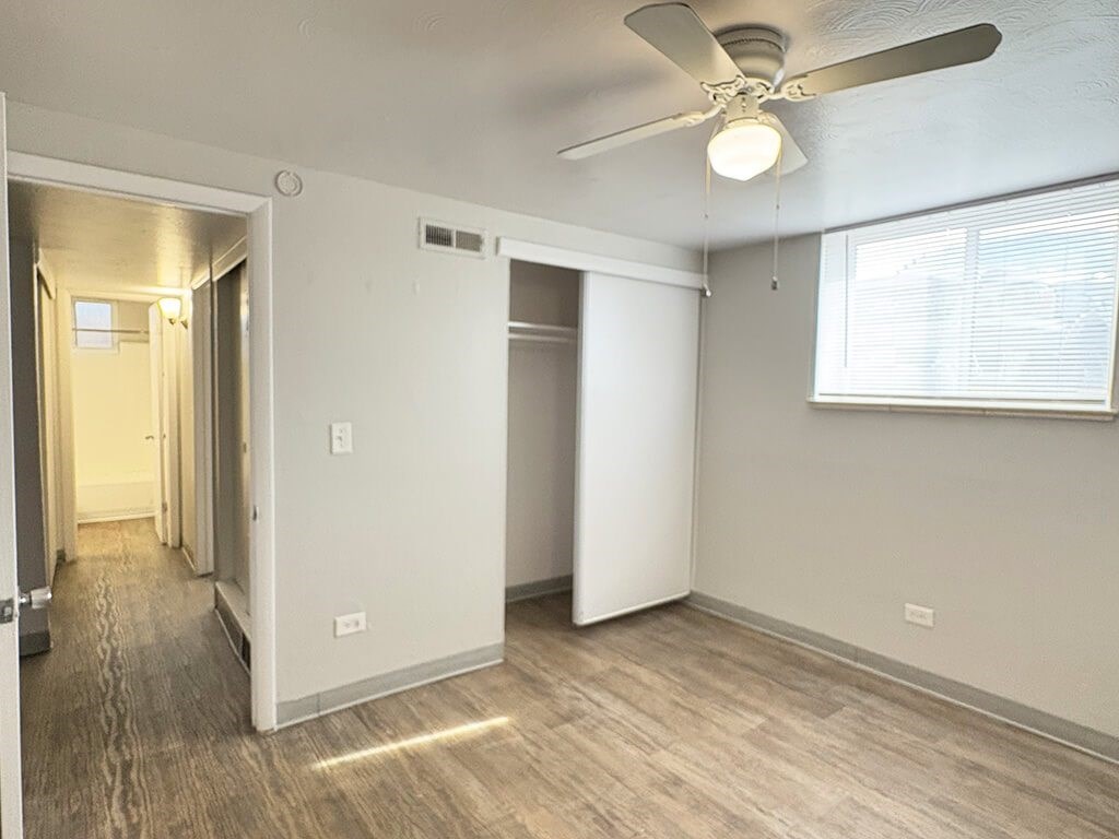 A room with a ceiling fan and a window with blinds.
