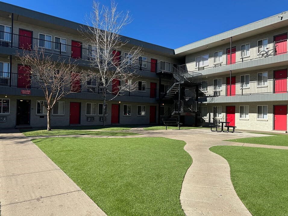 an apartment building with green grass and a playground