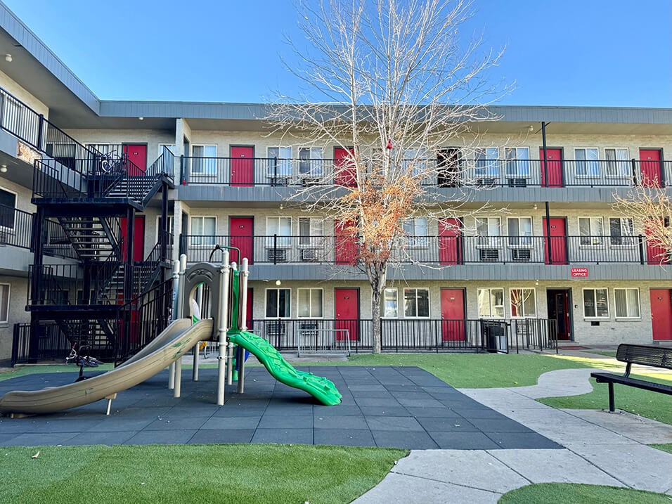 a playground with a slide in front of an apartment building