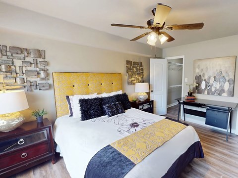 A bedroom with a bed, nightstands, and a ceiling fan.