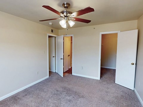 A room with a ceiling fan and carpeted floor.