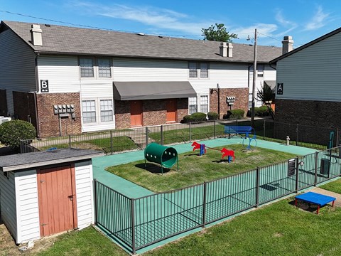 A playground area with a green fence and a red and blue slide.