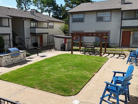 A small grassy area with a few chairs and a fire hydrant.