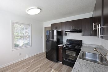 A kitchen with black appliances and wooden floors.